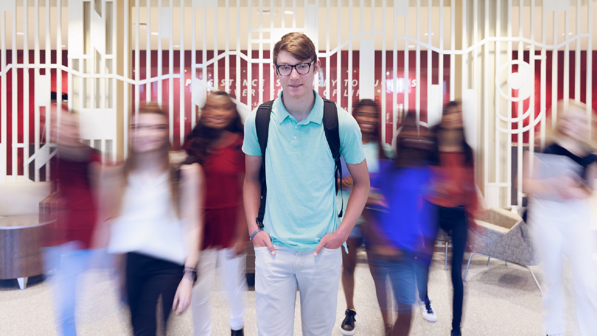 Confident student walks toward the camera as other students pass by in a blur